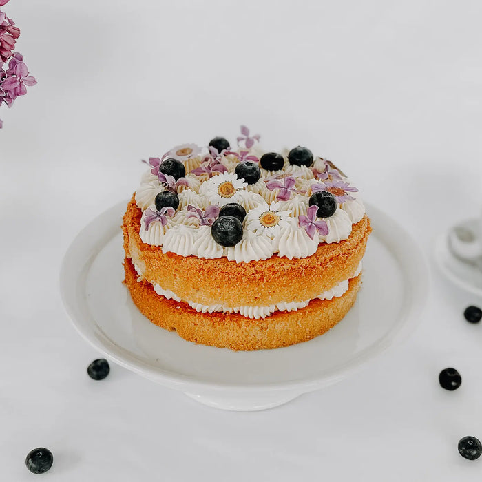 Ein Coffee Cheesecake auf einem Tortenplatte mit einem Kaffee und einem Blumenstrauß