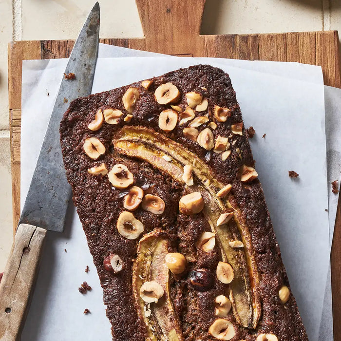 Ein Kaffee, Schoko & Haselnuss Bananenbrot auf einem Holzbrett