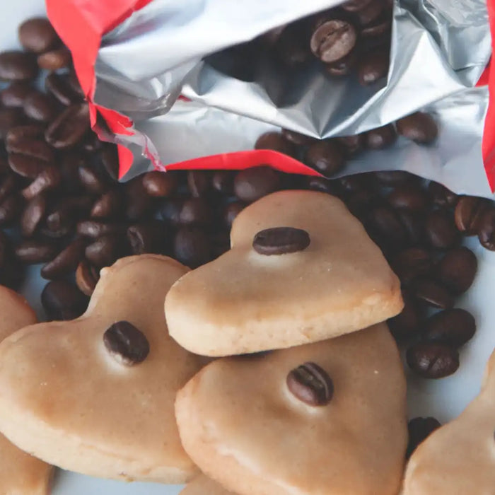 Kaffeekekse liegen inmitten von Kaffeebohnen des J. Hornig Spezial auf einem weißen Teller