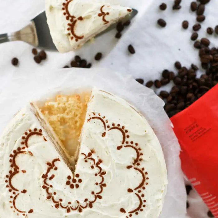 Die ganze Tiramisu Torte mit Kaffee von oben fotografiert daneben offene J. Hornig Spezial Kaffeepackungen aus denen Kaffee herausfällt 