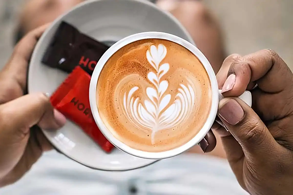 Eine Frau hält einen Cappuccino in der Hand