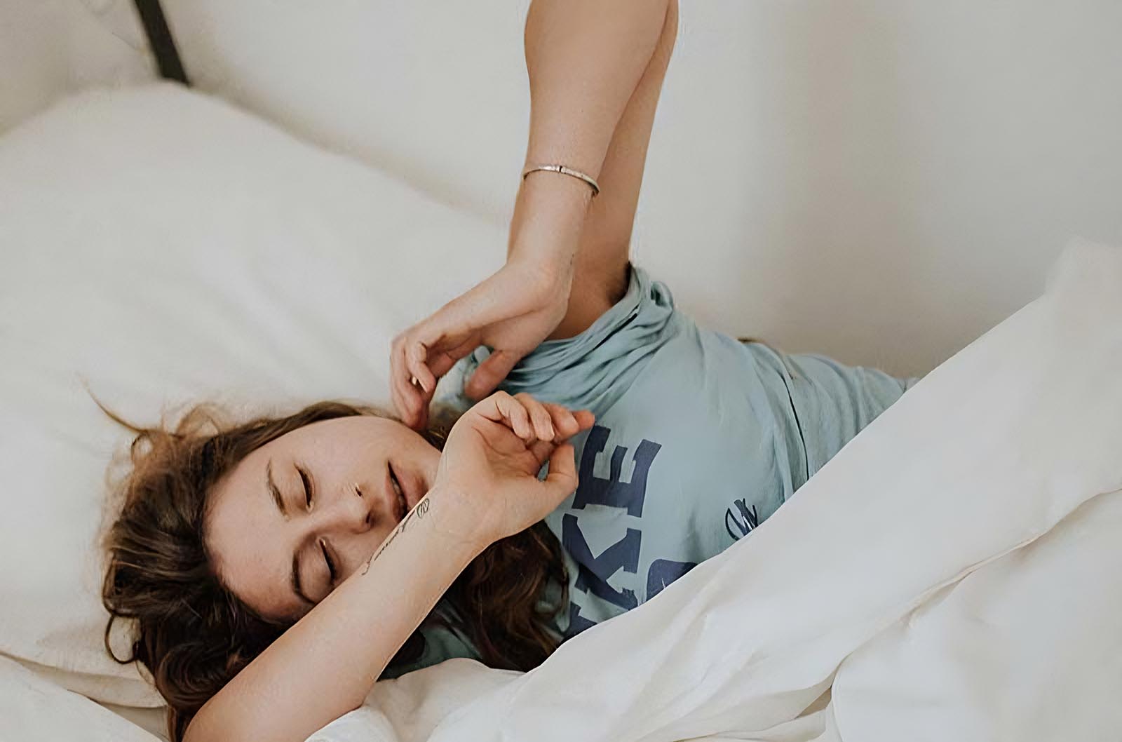 Frau liegt im Bett und dehnt sich
