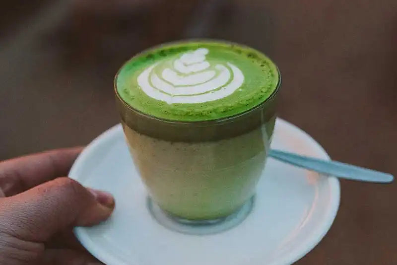 Brokkoli Latte mit Latte Art in der Hand haltend 