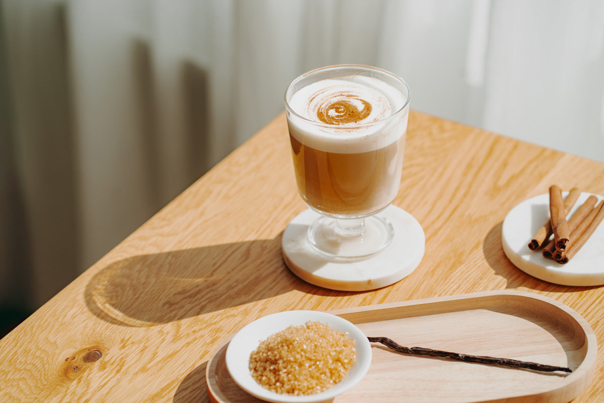 Zimtschnecken Latte Macchiato im Glas auf einem Tisch, neben den benötigten Zutaten