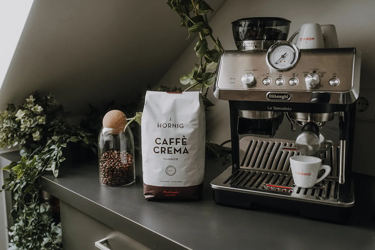 Eine Packung J. Hornig Caffe Crema Classico neben einem Siebträger in einem Büro.