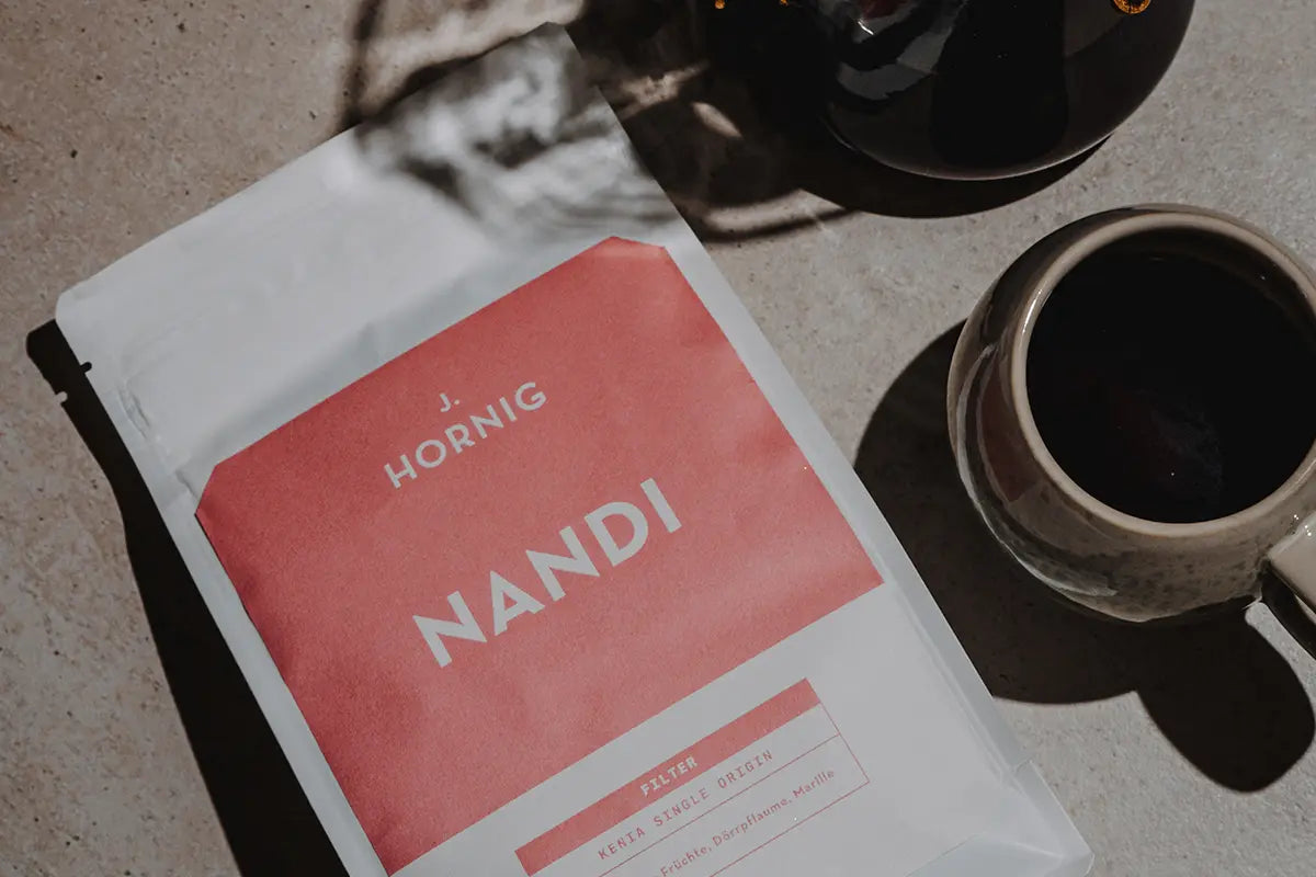 Eine Packung J. Hornig Nandi Spezialitätenkaffee Filter mit einer Kaffeetasse.