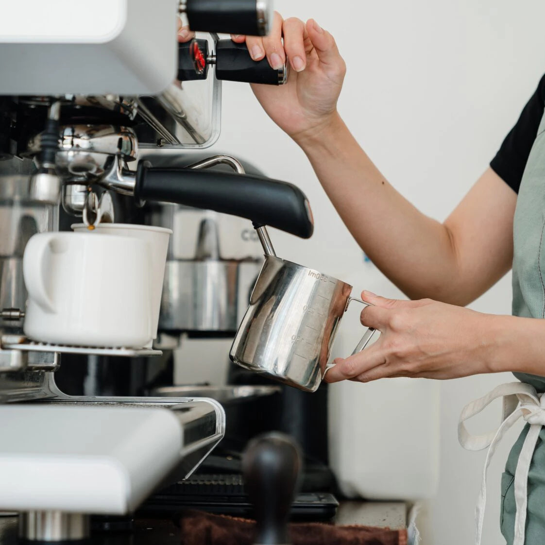 Eine Person bedient eine Siebträgermaschine.