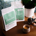 Zwei Packungen J. Hornig Spezialitätenkaffee Cerrado Espresso mit einer Espressotasse und einer Zimmerpflanze auf einem Holztisch