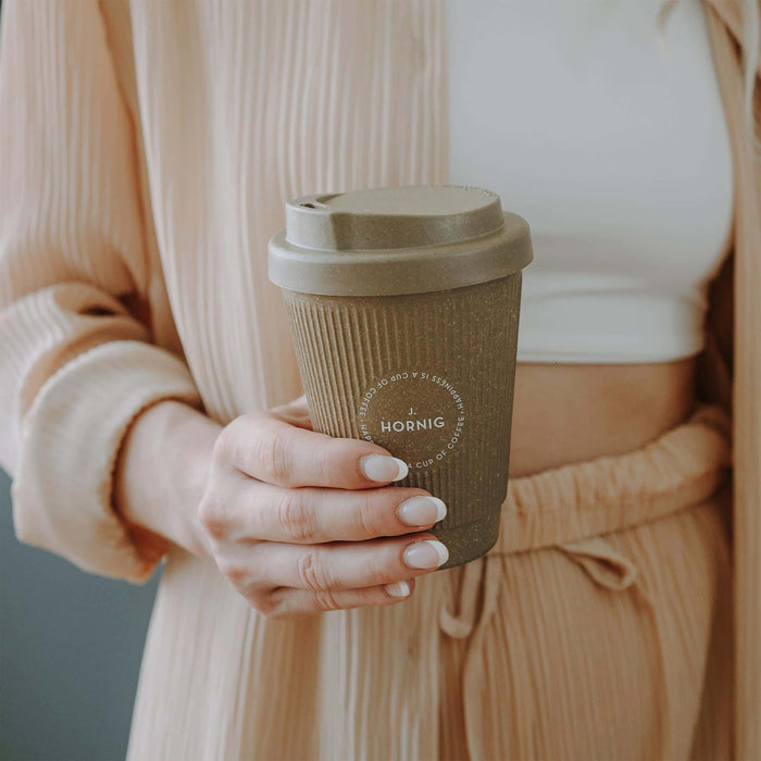 Eine Person hält einen Weducer Coffee to go Becher von J. Hornig in der Hand.