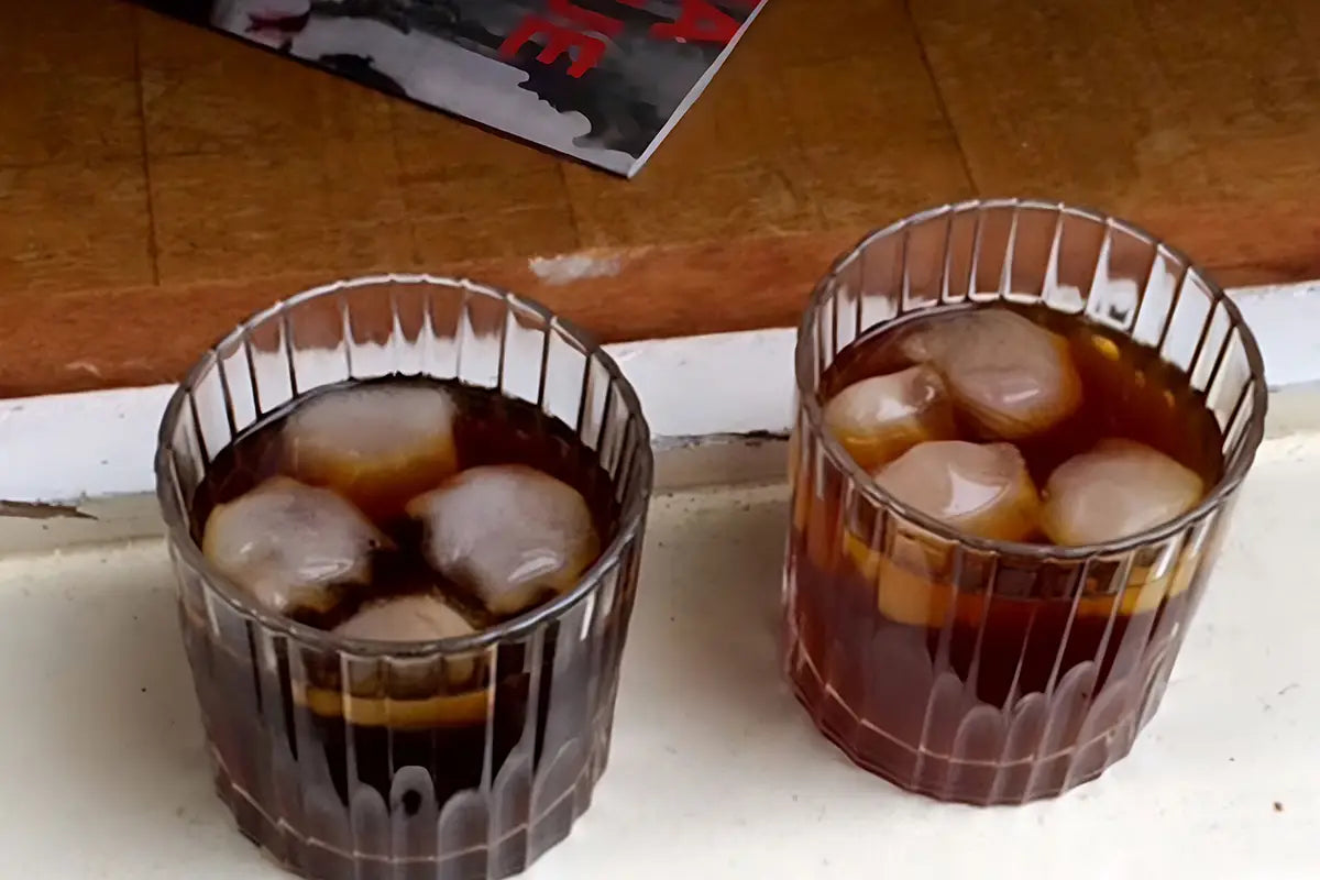 2 Gläser Kaffee mit Eiswürfeln im Glas auf einem weißen Untergrund stehend 