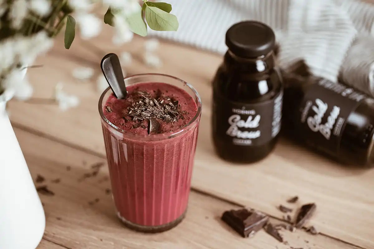 Auf einem Holztisch steht ein Heidelbeer-Kaffee-Smoothie mit Cold Brew Coffee