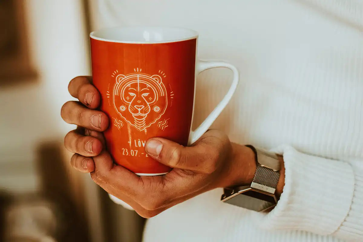 Person hält Kaffeetasse mit Sternzeichen Löwe in der Hand 