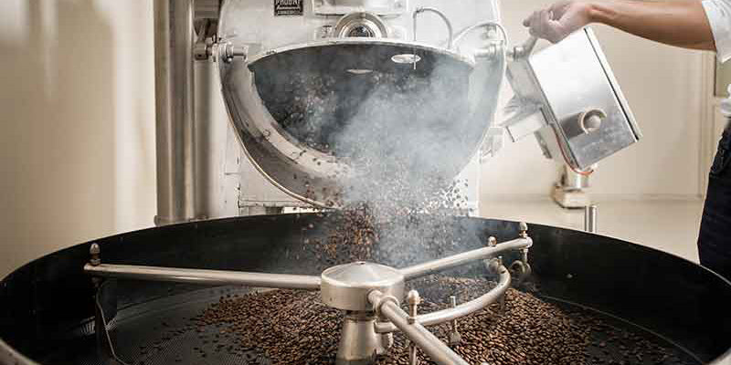 Eine Trommel wird mit Kaffee befüllt.