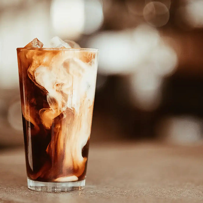 Ein Glas mit Cold Brew, Eis und Milch mit schönem Verlauf auf einem Tisch stehend