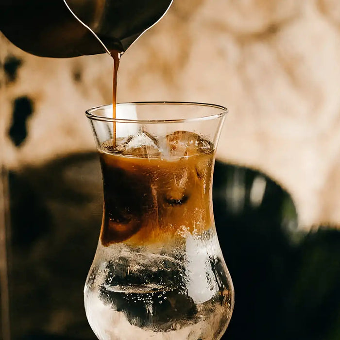 In ein Glas Tonic wird Espresso gegossen
