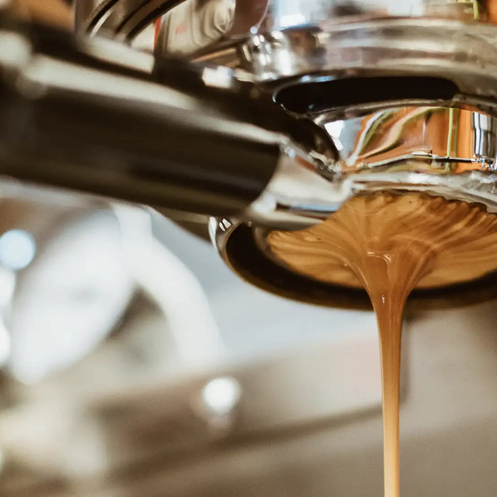 In einer Siebträgermaschine mit bodenlosem Siebträger sieht man die Crema des Kaffees und wie dieser herunterrinnt