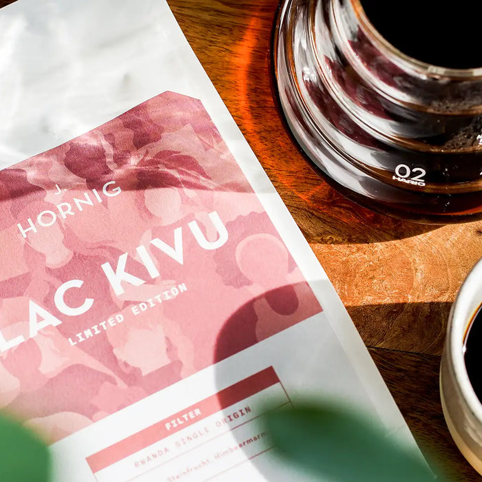 Eine Packung J. Hornig Spezialitätenkaffee Lac Kivu Filter mit einem Hario Dripper und einer Kaffeetasse