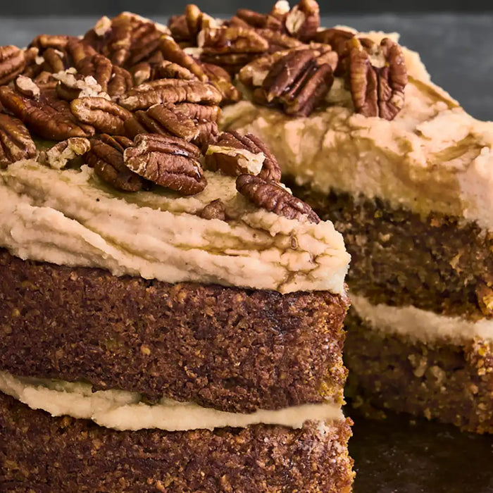 Vegane Kaffee-Karotten-Torte mit Pekannüssen garniert auf grau marmoriertem Untergrund