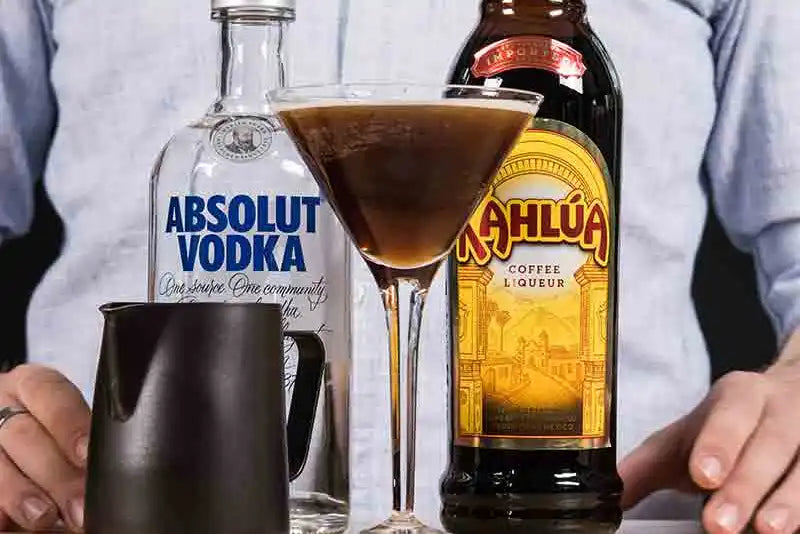 Eine Flasche Absolut Vodka und eine Flasche Kahlua mit einem Espresso-Martini Glas