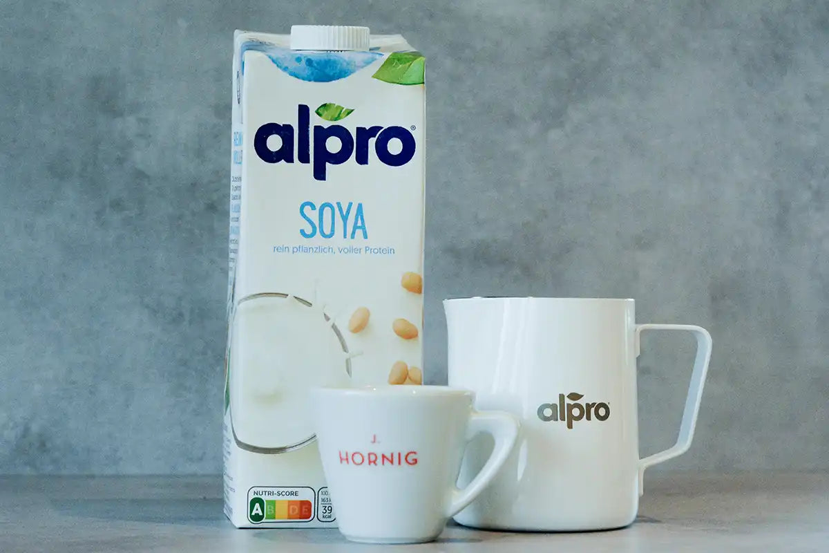 Eine Packung Alpro Soya steht neben einer J. Hornig Tasse und einer Alpro Milchkanne