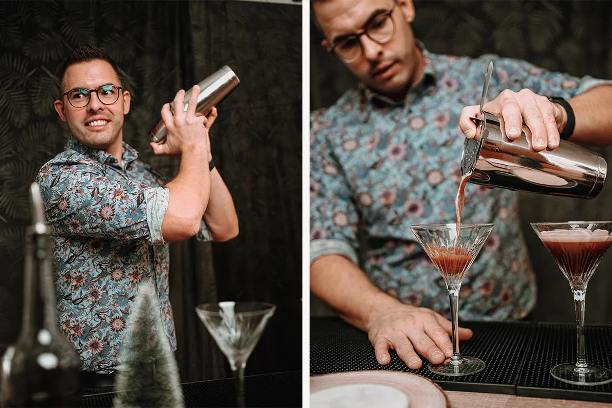 Ein junger Mann mixt einen Cocktail in einem bunten Hemd vor einem dunklen Hintergrund.