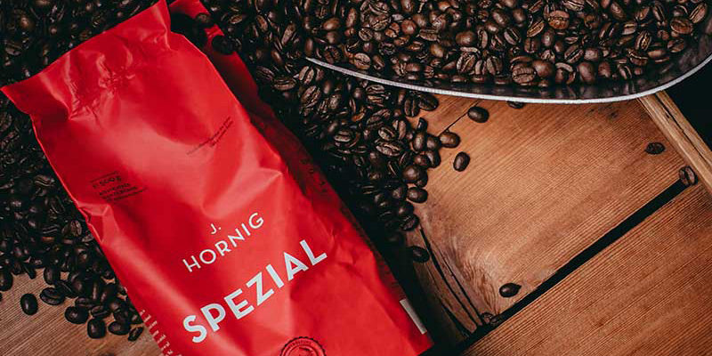 Eine Packung J. Hornig Spezial mit Kaffeebohnen auf einem Untergrund aus Holz.