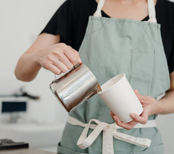 Eine Person bereitet einen Kaffee zu in heller Atmosphäre.