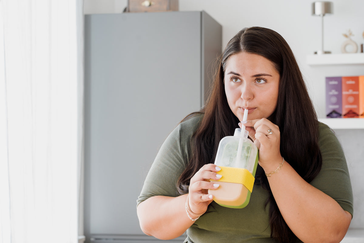 Eine Frau trinkt aus einen To-Go-Trinkbecher der eine eingebaute Eiswürfelfunktion hat.
