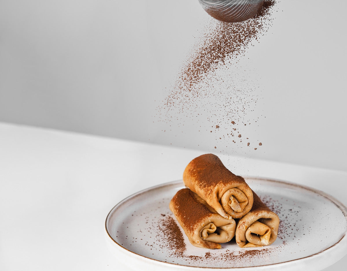 Teller mit fertigen Crêpes wird mit Backkakao bestäubt