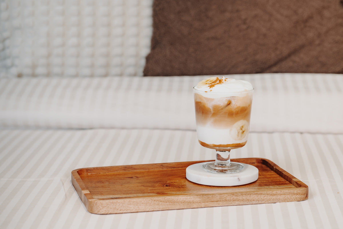 Der fertige Latte steht auf einem Holzbrett in einem gemütlichen Bett. 