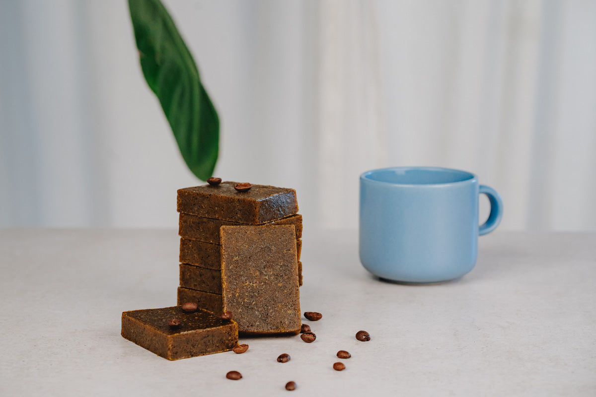 Auf einem Tisch ist selbstgemachte Kaffeeseife mit einer blauen Kaffeetasse.