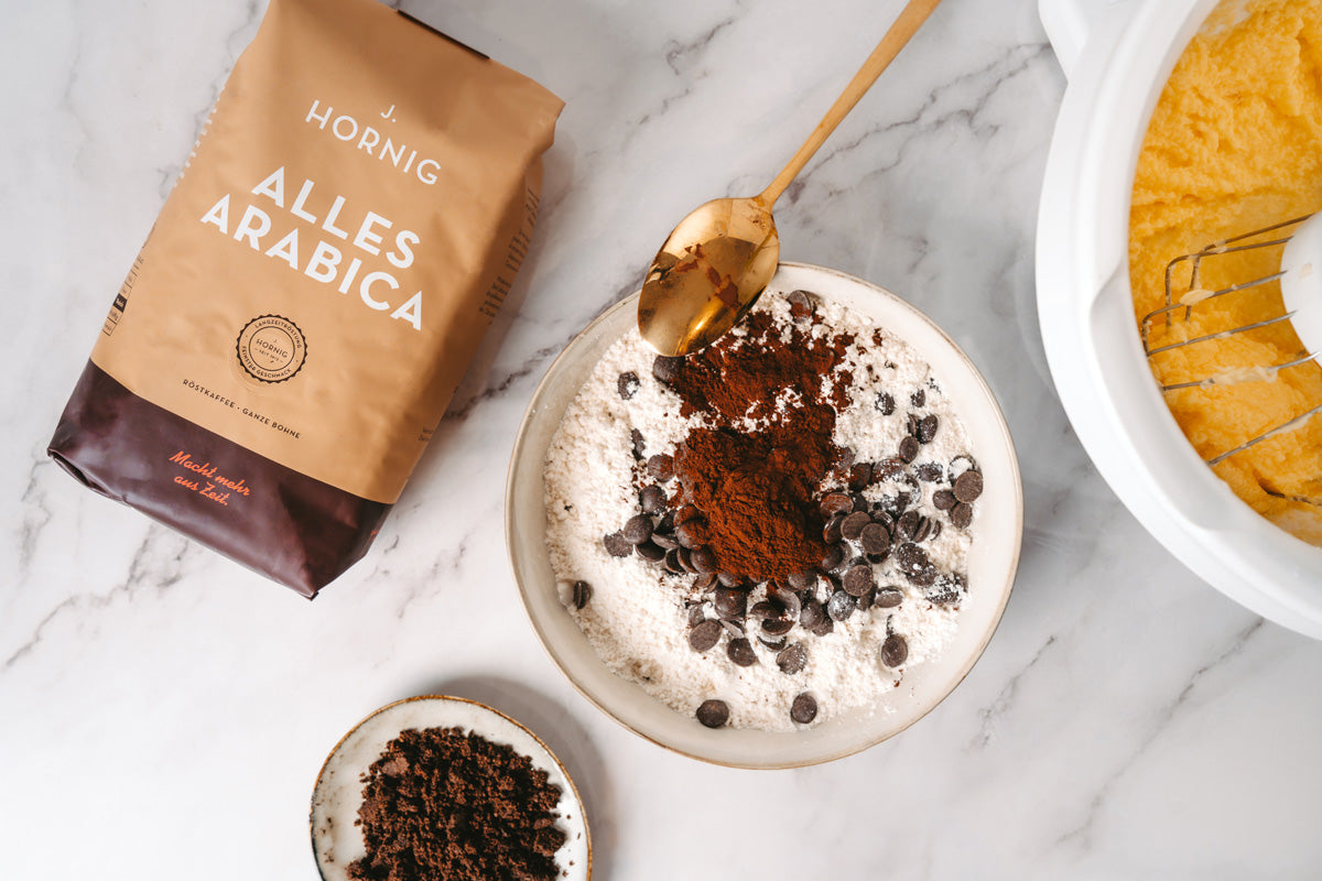 Vogelperspektive: Eine Schüssel mit gemischten trockenen Zutaten steht auf der Arbeitsfläche; daneben liegt eine Alles Arabica-Packung von J. Hornig.