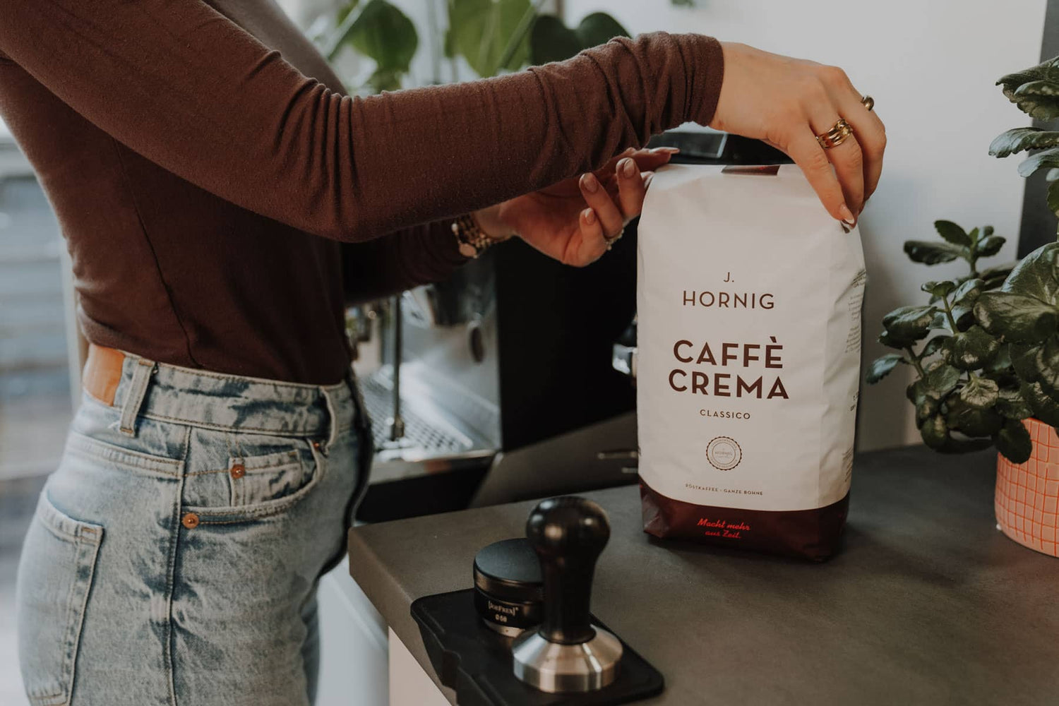 Person hält eine Packung Caffè Crema Classico in der Küche, bereit für die Zubereitung.