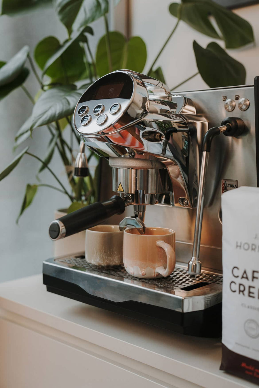 Espressomaschine bei der Zubereitung von zwei Shots, daneben eine Packung Caffè Crema Classico.