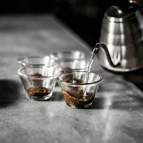 Gläser mit gemahlenen Kaffee auf einem Tisch mit einem Wasserkocher