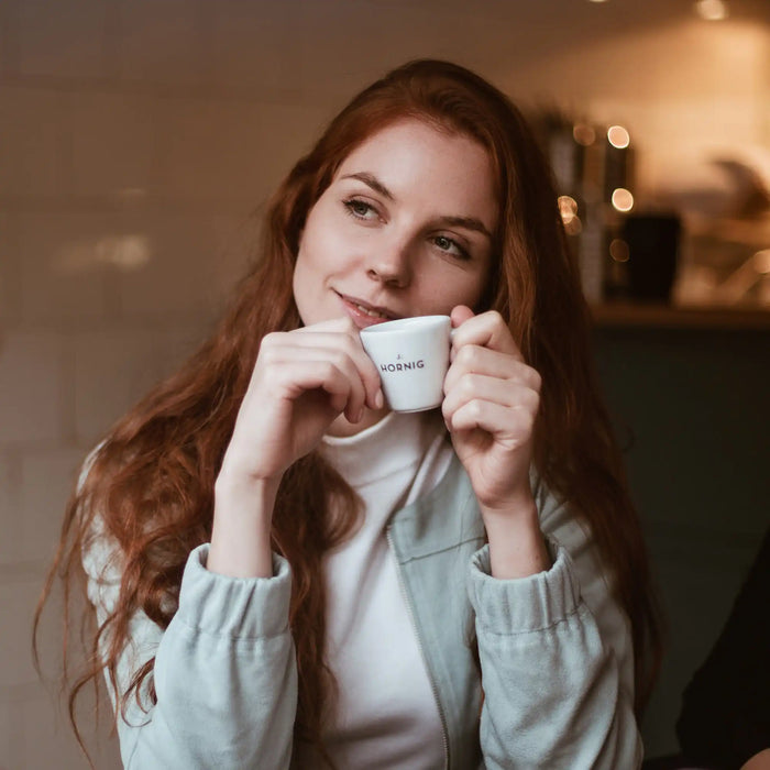 Eine junge Frau hält eine J. Hornig Espressotasse in einem Kaffeehaus.