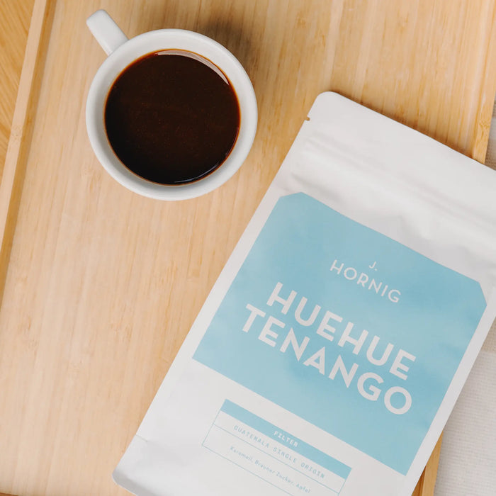 Top-Down-Aufnahme von J. Hornig Guatemala Huehuetenango Spezialitätenkaffee mit Tasse Kaffee.