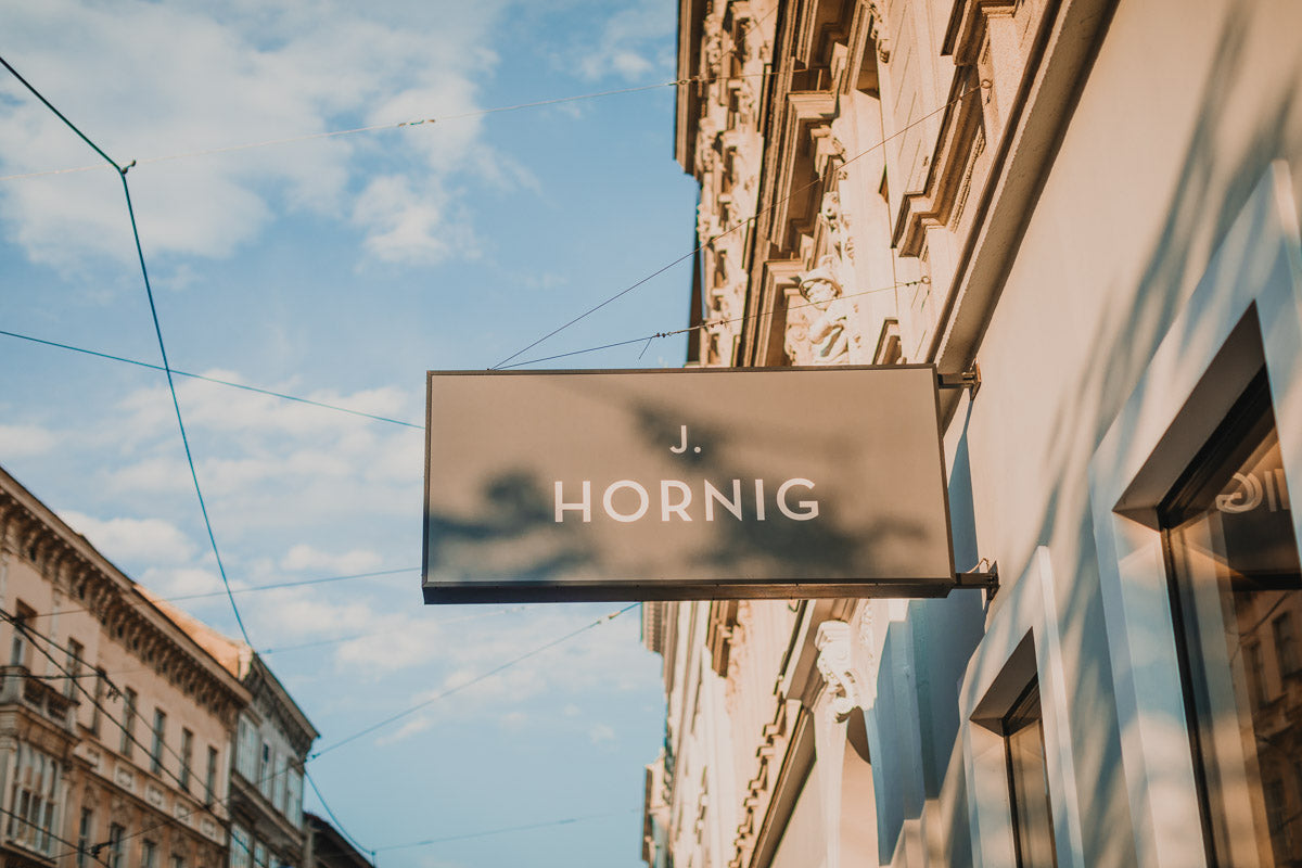 Ein Werbeschild mit dem Logo von J. Hornig auf einer Fassade in Wien