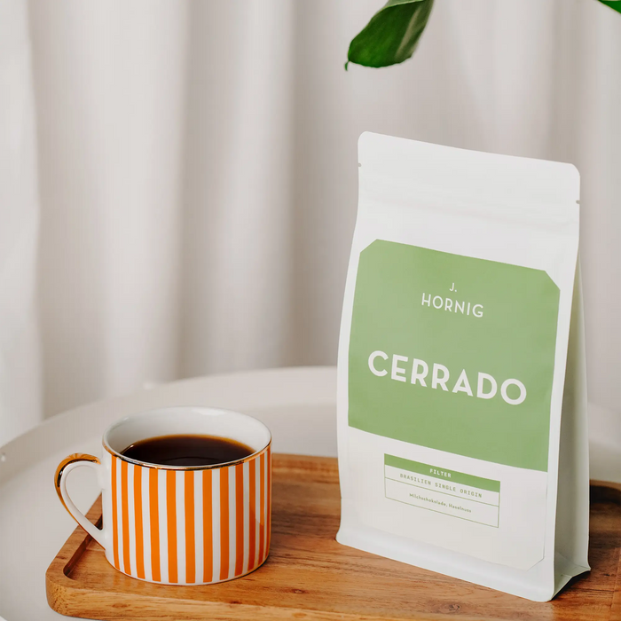 Eine Packung J. Hornig Spezialitätenkaffee Cerrado FIlter Single Origin Brasilien auf einem Holztisch mit weißem Tischtuch