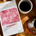 Eine Packung J. Hornig Spezialitätenkaffee Lac Kivu Filter Limited Edition liegend auf einem Holztisch mit einer gefüllten Kaffeetasse und einer Kaffeekanne