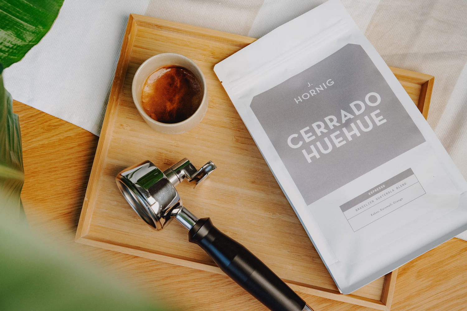 Packung J. Hornig Cerrado Huehue mit Siebträger und Espresso auf einem Holzbrett.