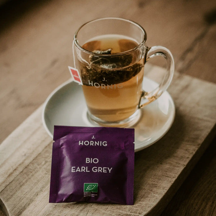 Eine Tasse Tee in einem J.Hornig Teeglas mit einer Einzelpackung Bio Earl Grey Tee