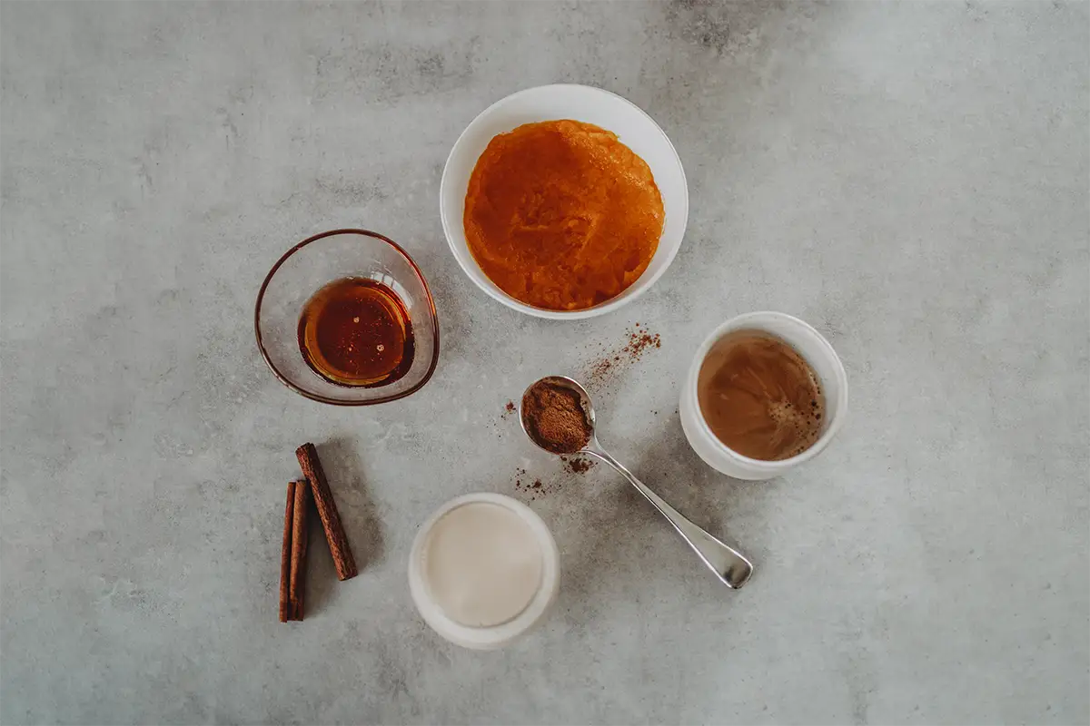Zutaten für einen Pumpkin Spice Latte in verschiedenen Schalen.